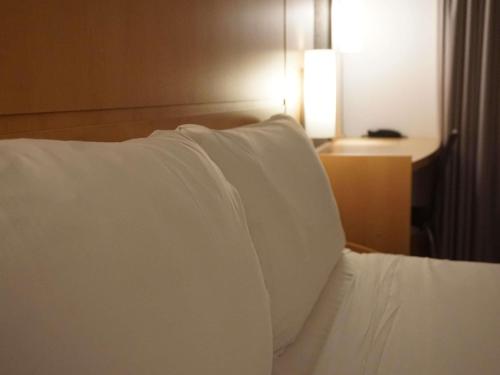 a close up of a bed with white pillows at Ibis Girona in Girona