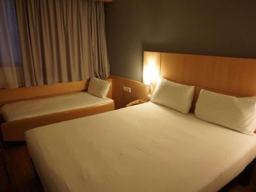 a hotel room with two beds and a window at Ibis Girona in Girona