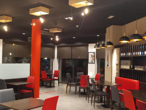 a dining room with tables and red chairs at Ibis Girona in Girona