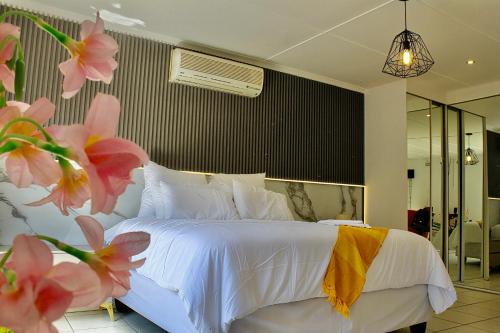 a bedroom with a white bed and pink flowers at Elroiairbnb in Amanzimtoti