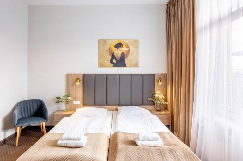 a bedroom with a bed and a chair and a window at Hotel Lothus in Wrocław