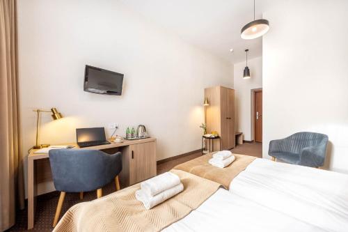 a bedroom with a bed and a desk with a laptop at Hotel Lothus in Wrocław