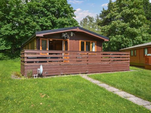 a small cabin in a yard with a green lawn at Lomond View Lodge in Rowardennan