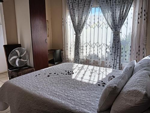 a bedroom with a bed and a window with a fan at Desita La' Guesthouse in Rustenburg
