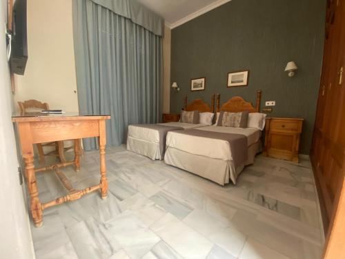 a bedroom with two beds and a wooden table at Hotel La Española in Chipiona