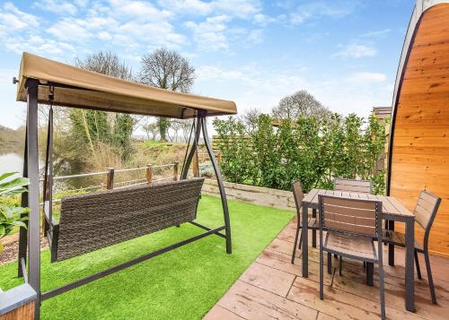 a patio with a table and chairs and an umbrella at Peacock Lake Glamping in East Bridgford