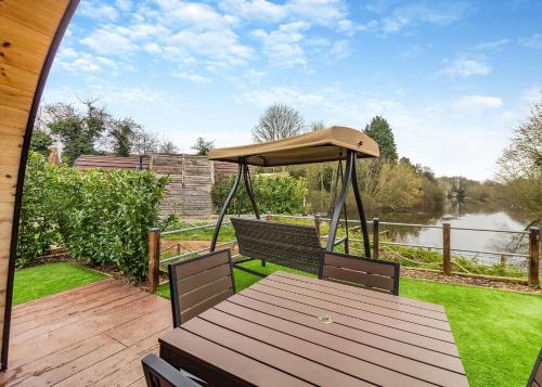 a wooden table with an umbrella on a deck at Peacock Lake Glamping in East Bridgford