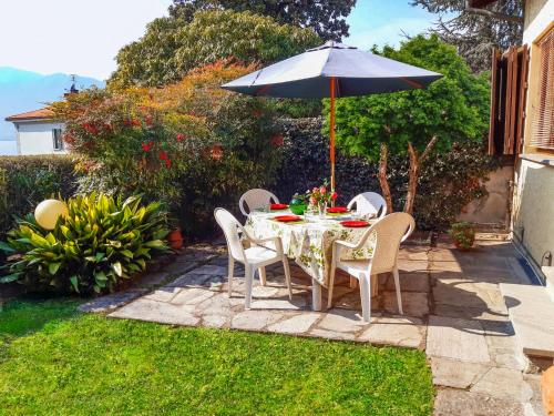 a table and chairs with an umbrella in a garden at Villino Alborella in Verbania