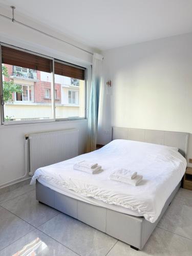 Una cama blanca en una habitación con ventana. en Elegant and Comfortable Studio Jouvenet, en París