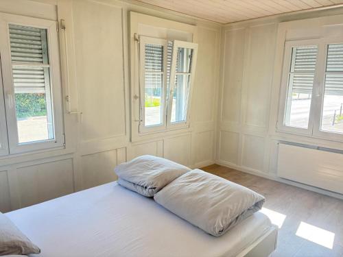 Habitación blanca con 1 cama y 2 ventanas en Charmante 2-Zimmer EG Wohnung in Heiden, en Heiden