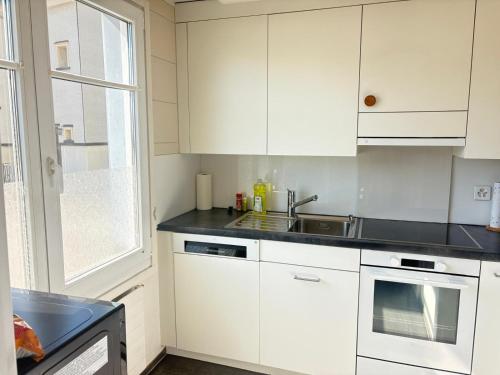 Una cocina con gabinetes blancos y un fregadero y una ventana. en Charmante 2-Zimmer EG Wohnung in Heiden, en Heiden