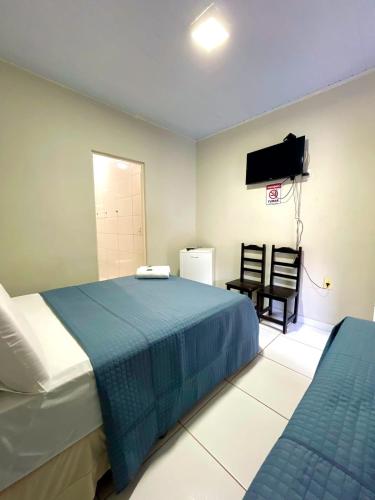 a bedroom with a bed and a tv and a chair at Pousada dos Nobres in Estivado