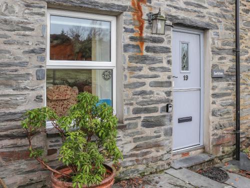 a stone house with a white door and a plant at Garthfain in Dolwyddelan