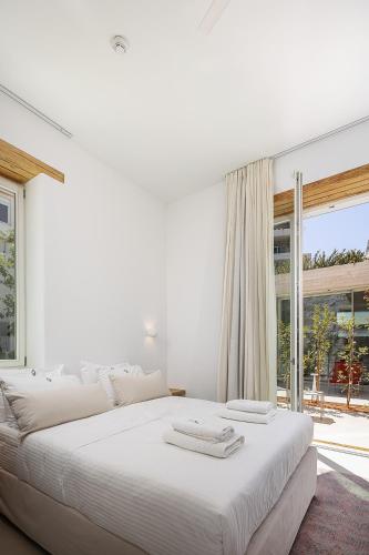 una camera bianca con un grande letto e una grande finestra di Hub Hospitality a Chania