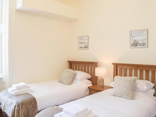 Dos camas en una habitación con paredes blancas. en Sorbie Villa, en Stevenston
