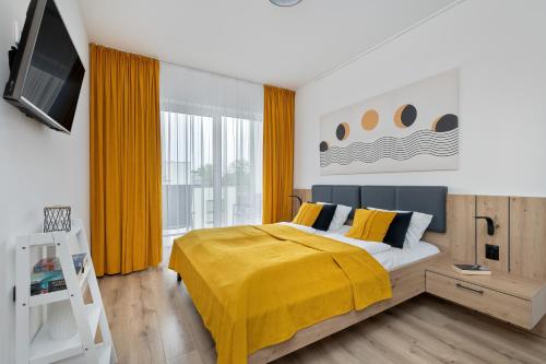 a bedroom with a bed with a yellow blanket at Stela Water Side Apartment - Swimming Pool & Sauna by Renters Prestige in Dziwnów