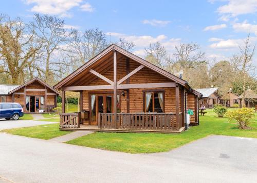 a log cabin with a porch and a car at Tilford Woods Lodge Retreat in Farnham