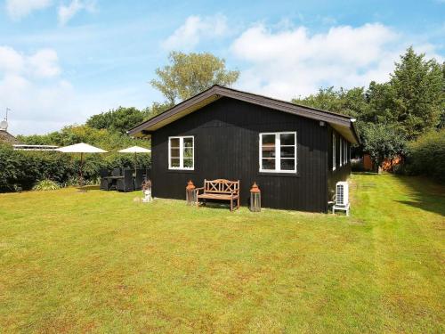 a black house with a bench in a yard at 7 person holiday home in Kirke Hyllinge-By Traum in Kirke-Hyllinge