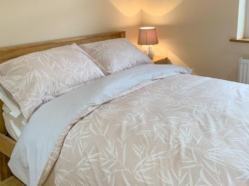 a bed with a white comforter and pillows at Catcleugh Bridge View in Kielder