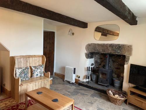 a living room with a stone fireplace and a table at Penny Black Cottage in Ingleton