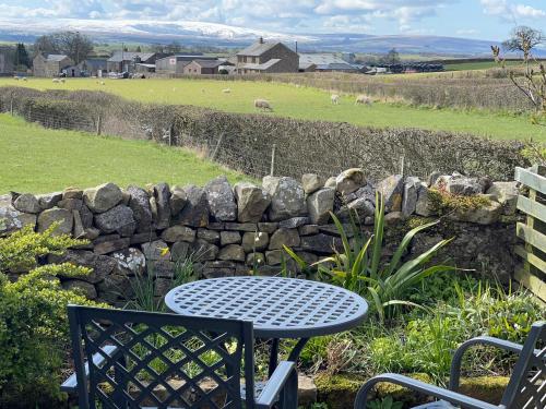 a table and chairs sitting next to a stone wall at Penny Black Cottage in Ingleton