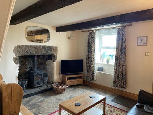 a living room with a stone fireplace and a television at Penny Black Cottage in Ingleton
