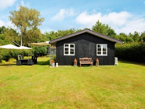 a black tiny house on a grass field at 7 person holiday home in Kirke Hyllinge-By Traum in Kirke-Hyllinge