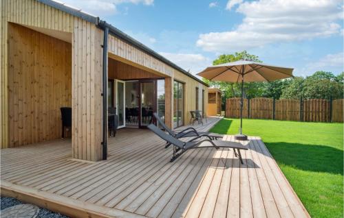 a wooden deck with a bench and an umbrella at Cozy Home In Samsø With Kitchen in Onsbjerg