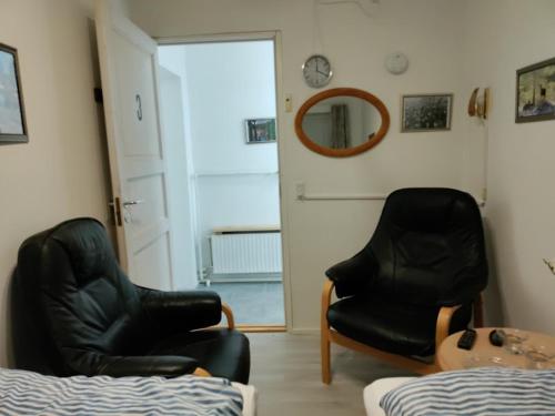 two black chairs in a room with a bed and a mirror at Pejsehaven in Nørre Snede