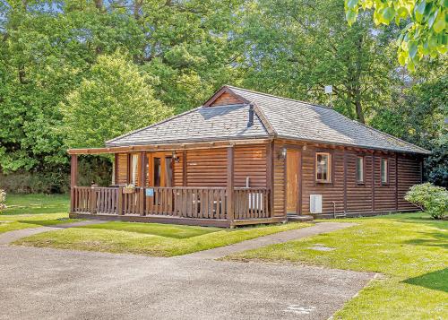 a large wooden cabin with a wooden deck at Tilford Woods Lodge Retreat in Farnham