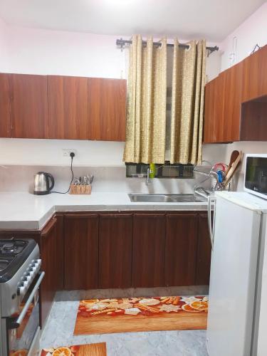 a kitchen with wooden cabinets and a sink and a refrigerator at Kate's Ksm CBD apartments 3br2br1br O7Oo1FourFour22Eight in Kisumu
