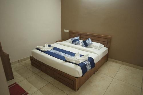 a bedroom with a bed with blue and white pillows at Hamai Grand Home Stay in Ambalavayal