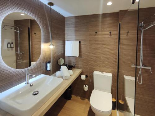 a bathroom with a sink and a toilet and a mirror at Flacalco Hotel & Apartments in Cala Ratjada