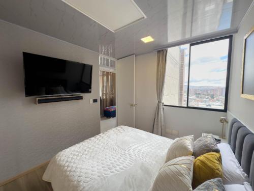 a person laying on a bed in a bedroom with a tv at Top views, airport, Salitre, American embassy, parking in Bogotá