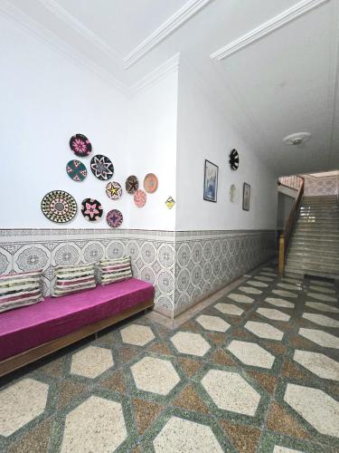 a room with a purple couch and plates on the wall at KARAZ Homestay Grand appartement avec rooftop in Monte ʼArrouit