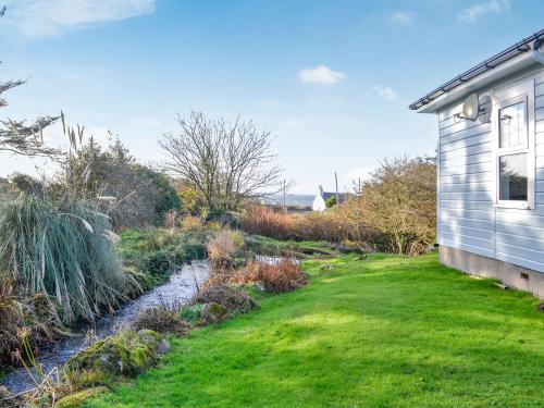 a house with a grass yard next to a stream at Clarksburn Blue in Monreith