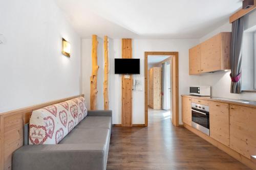 a living room with a couch and a kitchen at Hotel Residence Olympia Sarntal in Sarntal