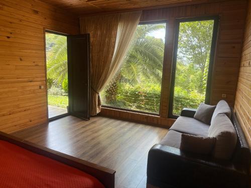a living room with a couch and a large window at Chalet Ochos Qokhi in Kvariati