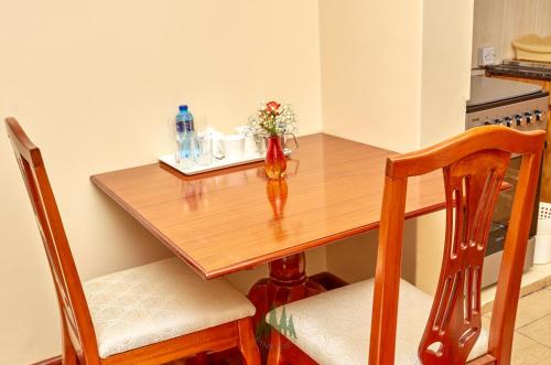 a wooden table with a vase of flowers on it at Pinetree Gardens Residence in Eldoret