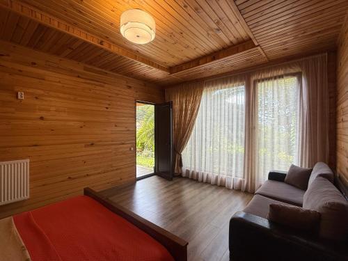 a living room with a couch and a large window at Chalet Ochos Qokhi in Kvariati