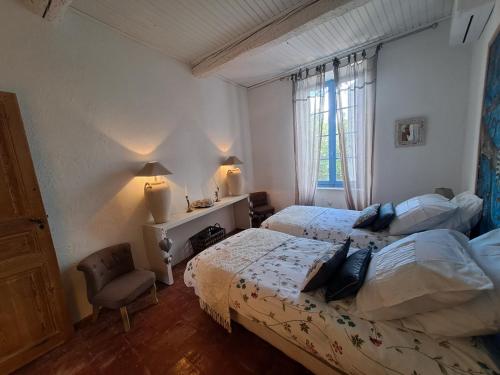 a bedroom with two beds and a chair and a window at La maison SPA, PISCINE et CLIMATISATION in Sainte-Vallière