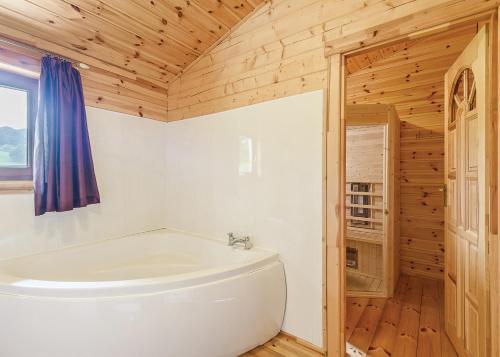 a white tub in a bathroom with a wooden ceiling at Trewythen Lodges in Caersws