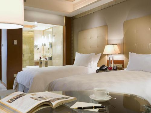 a hotel room with two beds and a table with a book at Sofitel Harbin in Harbin