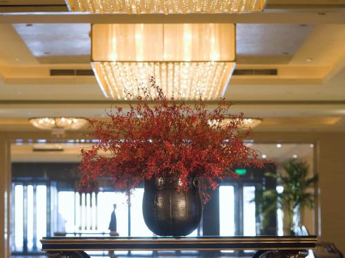 a vase with red flowers sitting on a table in a building at Sofitel Harbin in Harbin