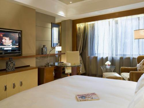 a hotel room with a bed and a television at Sofitel Harbin in Harbin