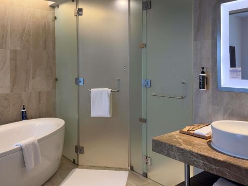 a bathroom with a shower and a tub and a sink at Novotel Pune Viman Nagar Road in Pune