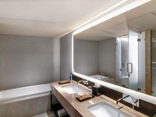 a bathroom with two sinks and a large mirror at Novotel Pune Viman Nagar Road in Pune
