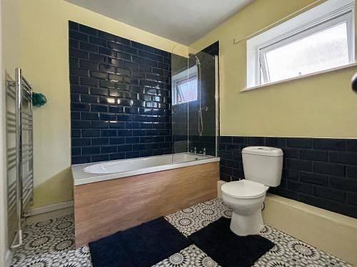a bathroom with a tub and a toilet and a window at Flodden Apartment in Wooler