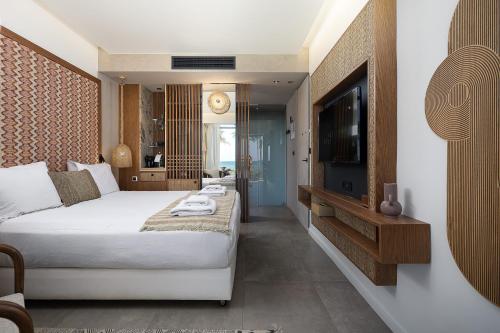 a bedroom with a bed and a flat screen tv at La Mer Resort Spa Crete in Georgioupolis