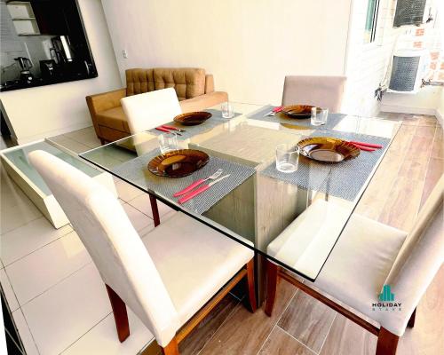 a glass dining room table with white chairs and a table and chairsktop at Brisa do Mar Apartments in Fortaleza